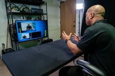 A man is sitting at a table in front of a television.