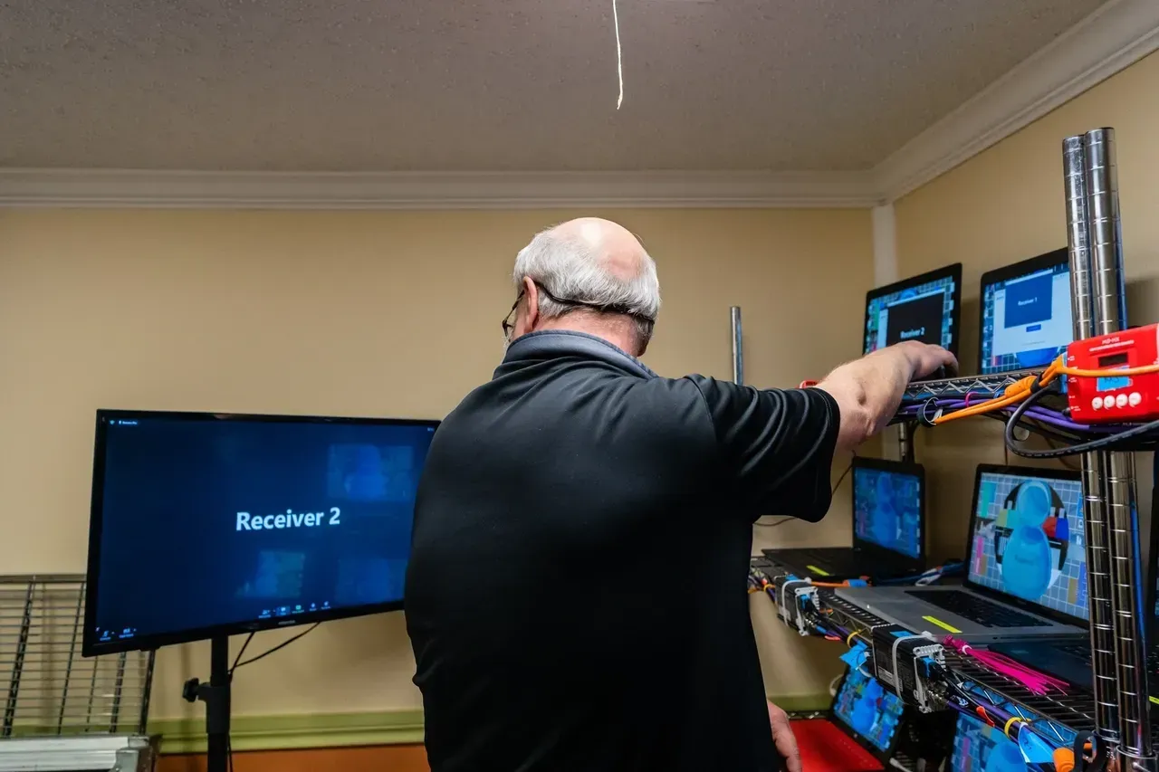 A man is standing in front of a computer monitor in a room.