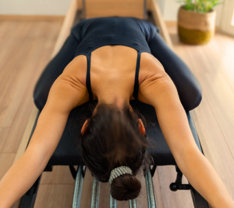 An image of a woman using a Pilates Reformer for Pilates Training.