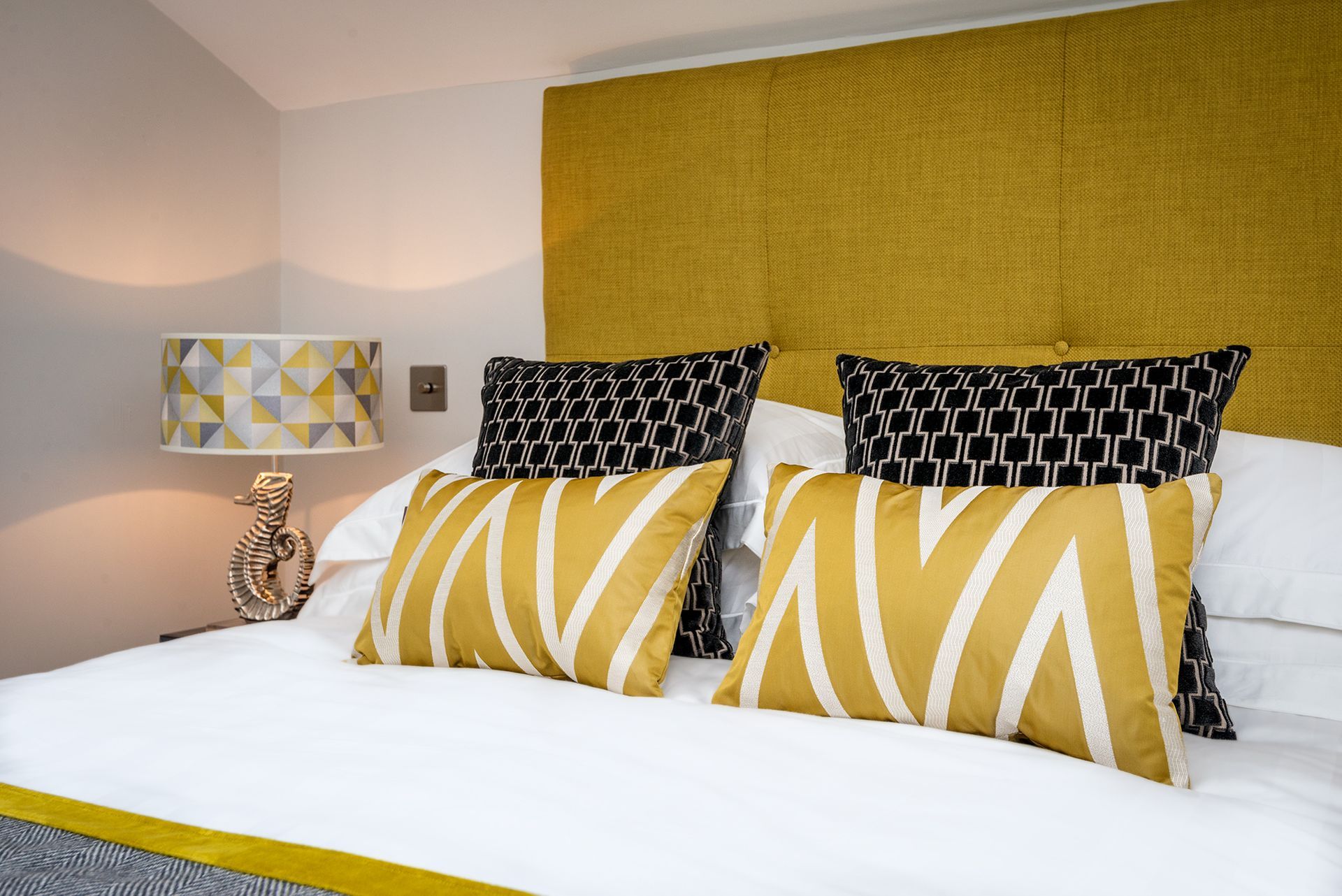 a bed with a yellow headboard and black and white pillows
