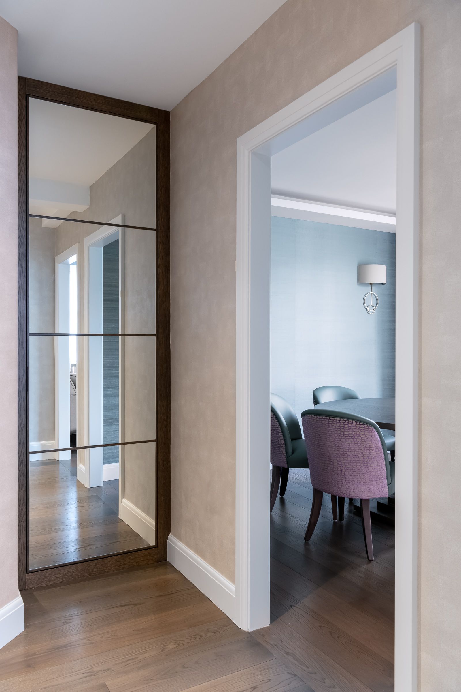 a hallway with a large mirror on the wall leading to a dining room 