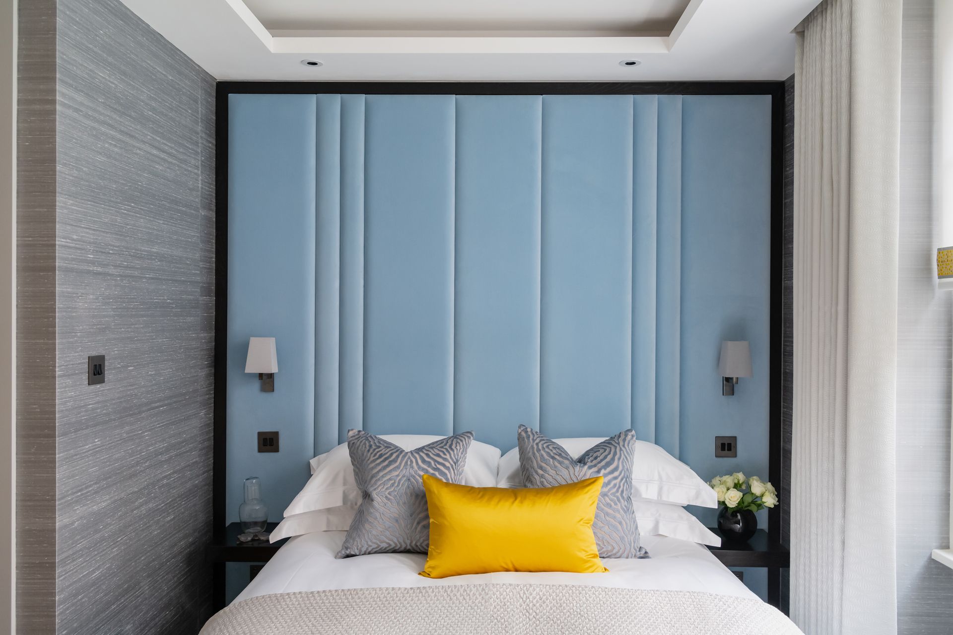 a bedroom with a blue headboard and a yellow pillow on the bed 