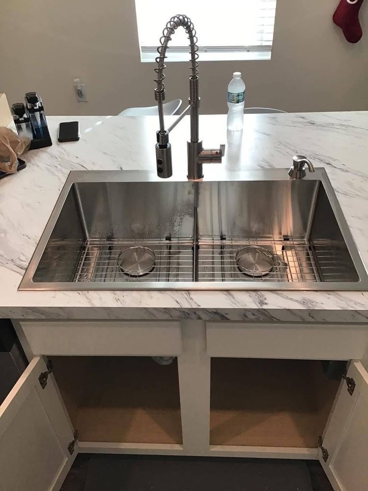 A stainless steel kitchen sink is sitting on top of a marble counter top.