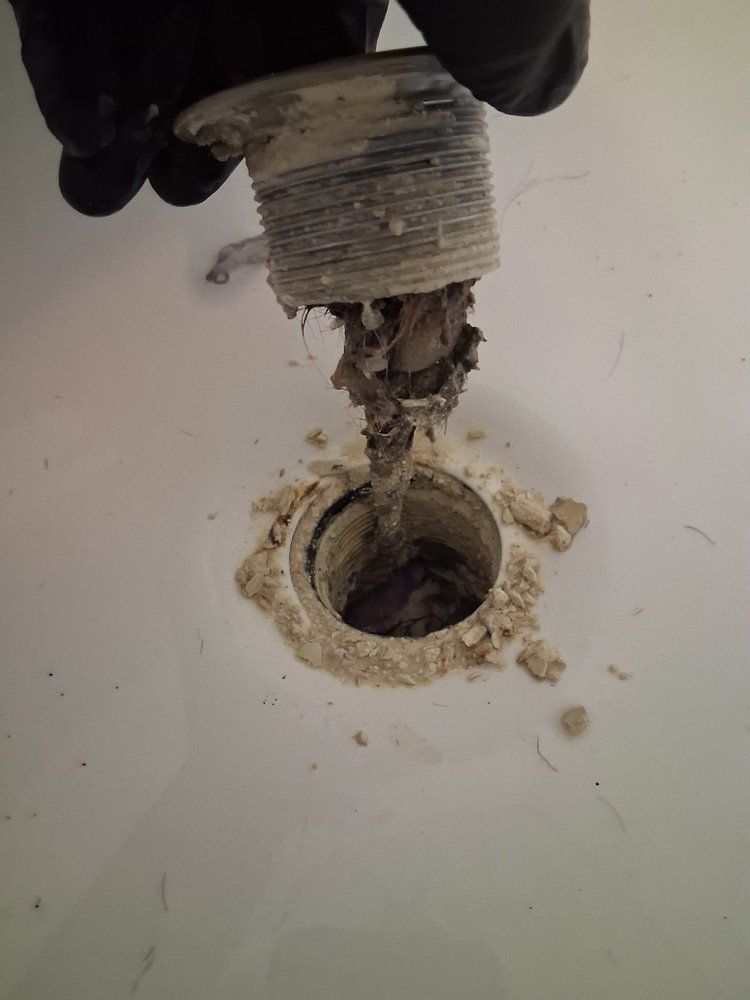 A person is cleaning a sink drain with a plunger.