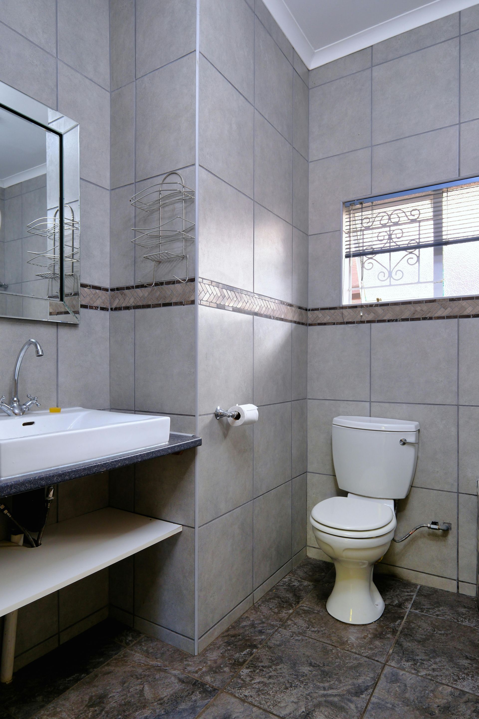 A bathroom with a toilet , sink and mirror.