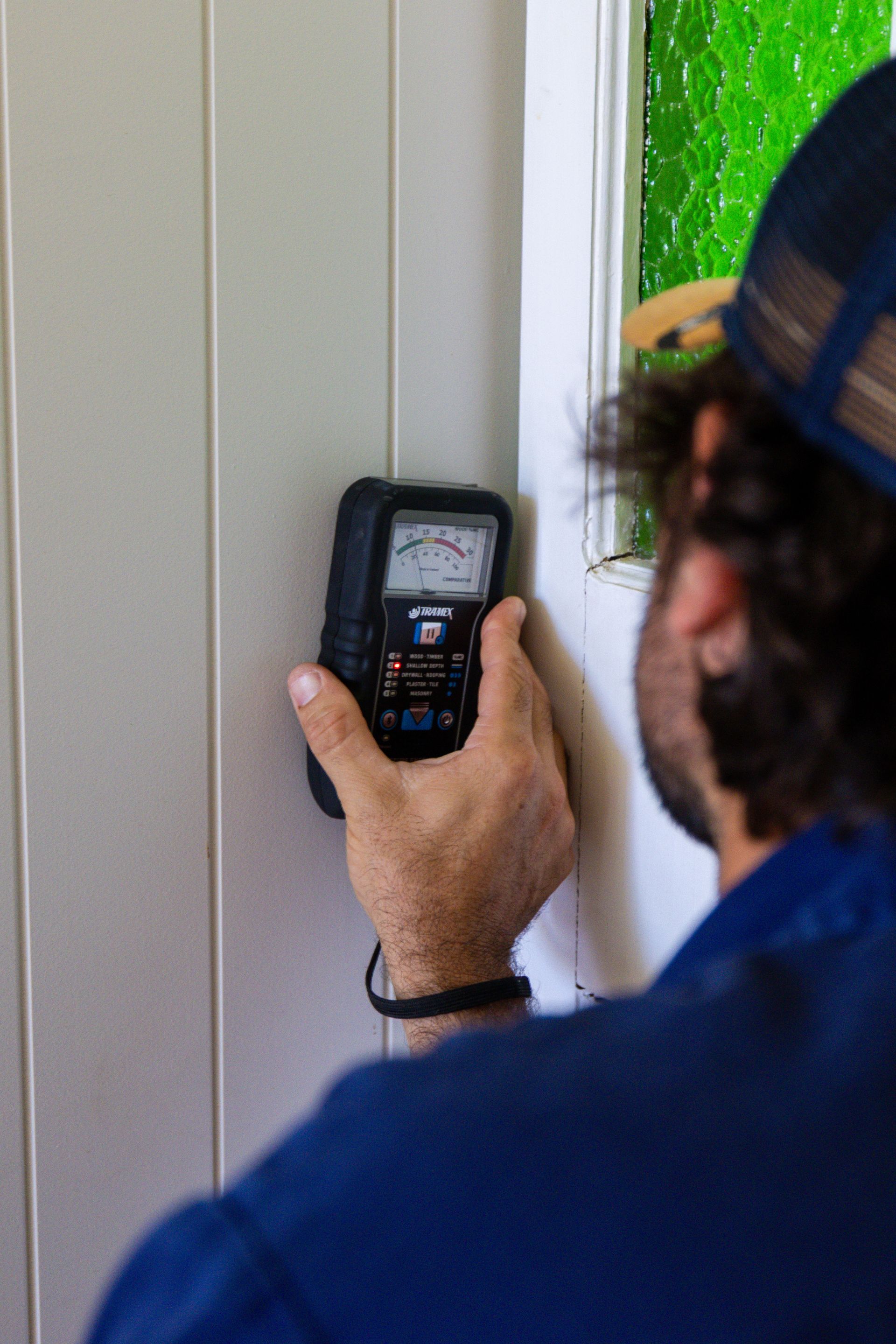 A Man Is Testing A Wall With A Monitor — ROGA Build Solutions in Atherton, QLD