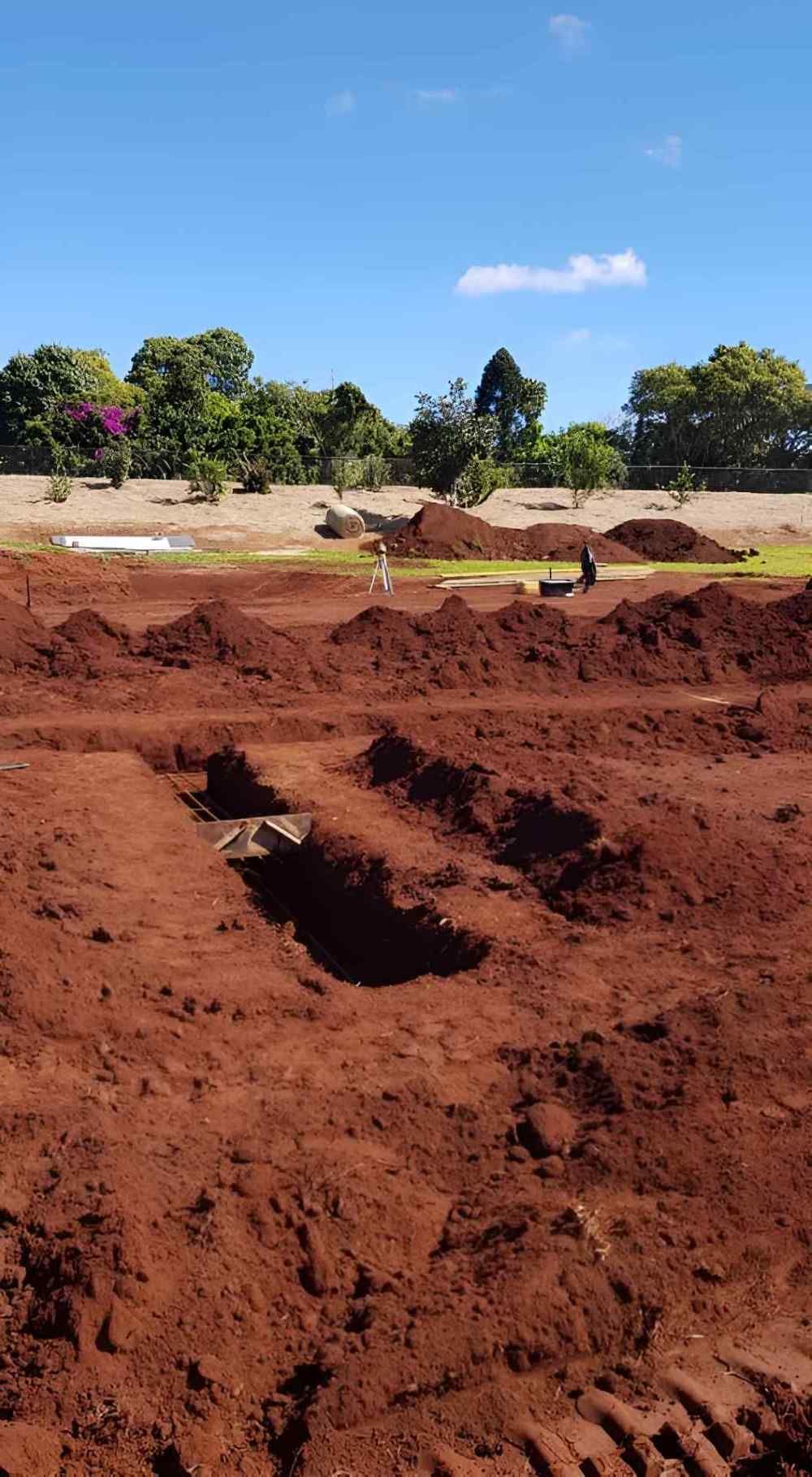 A Large Pile of Dirt in a Field With Trees in the Background — ROGA Build Solutions in Mareeba, QLD