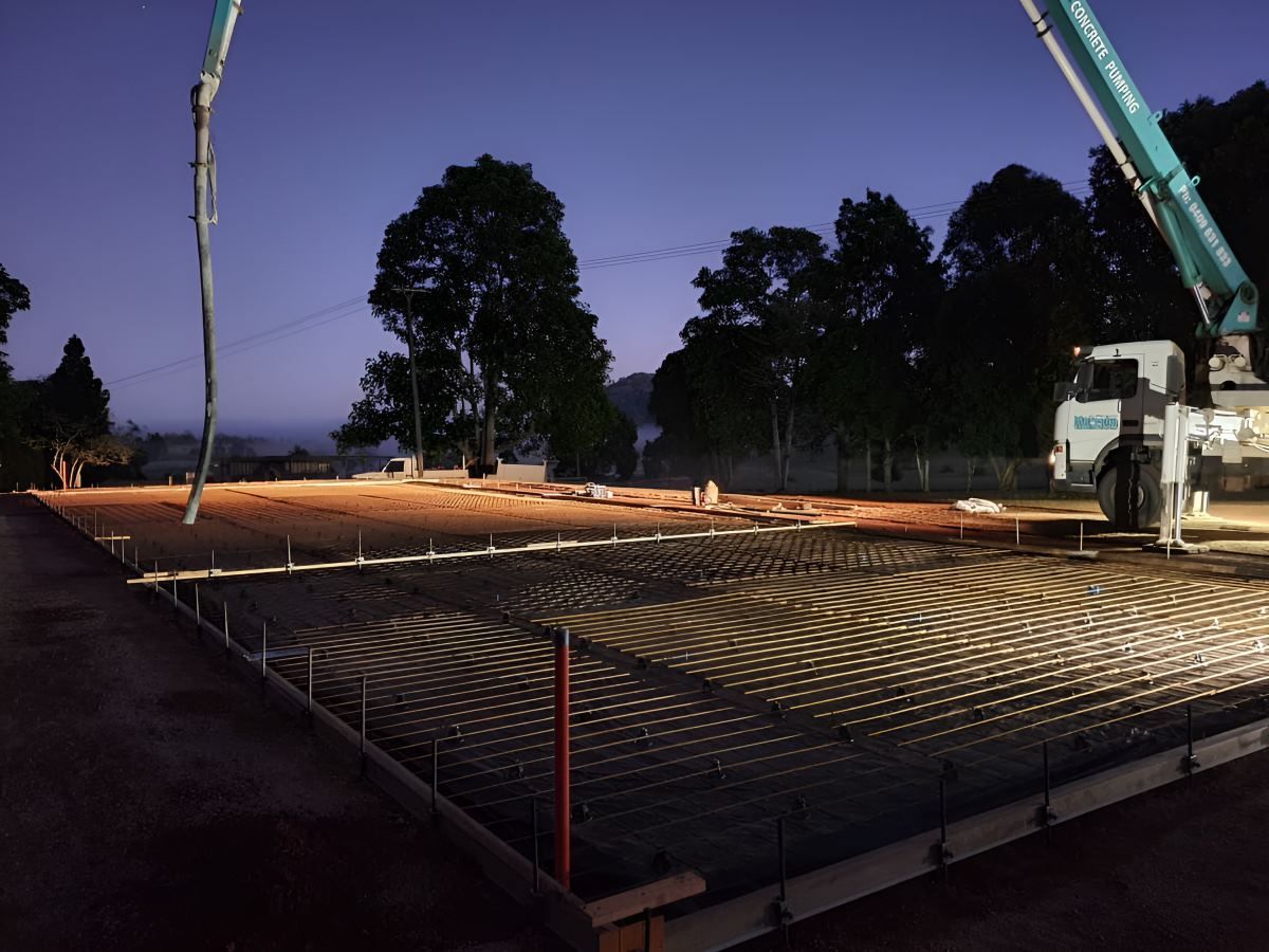 A Construction Site is Lit Up at Night With a Crane in the Background — ROGA Build Solutions in Atherton, QLD