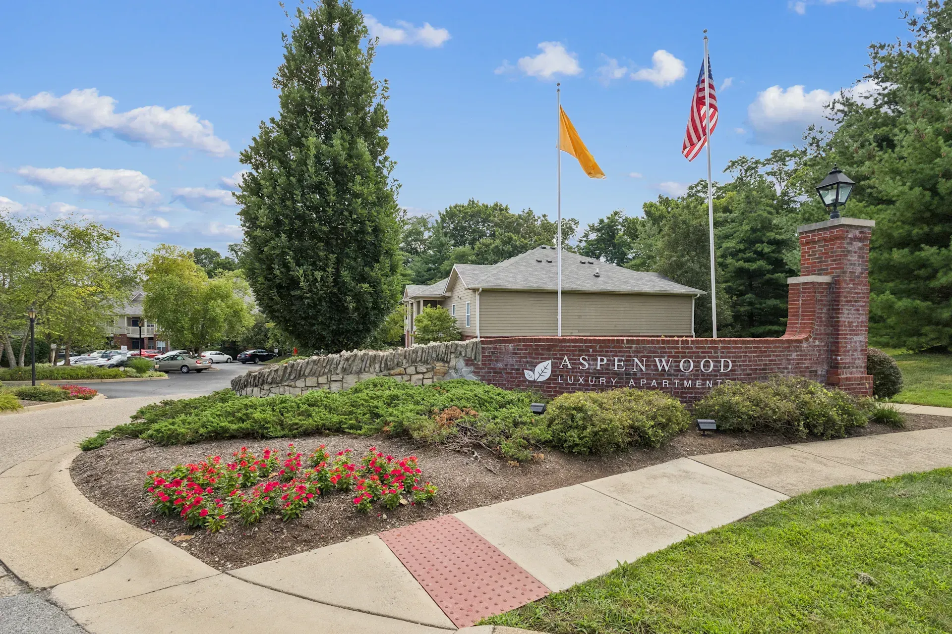 Sign for Applewood community with flags, brick accents, and landscaping.