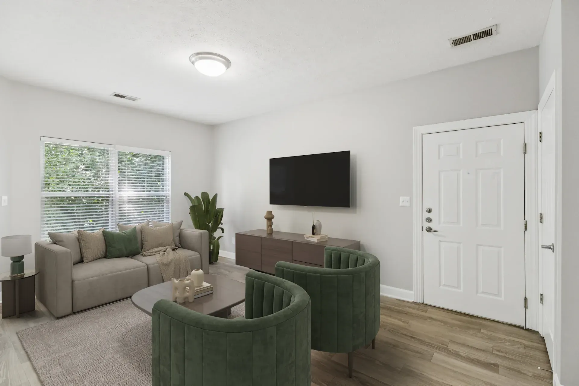 Living room with green armchairs, a couch, TV, and wooden floor.