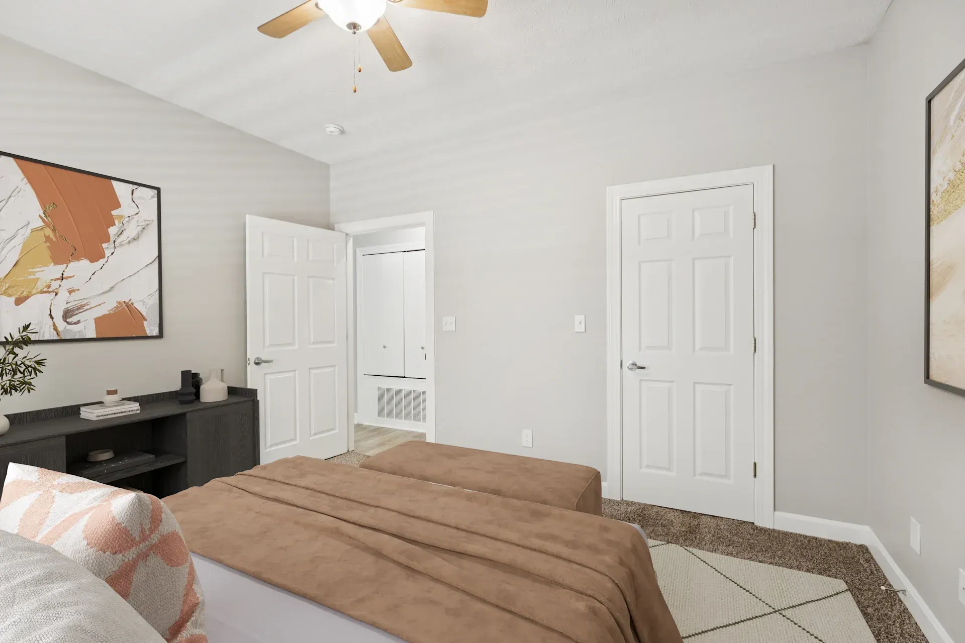 Bedroom with a bed, artwork, and two white doors. Pale gray walls and a ceiling fan.