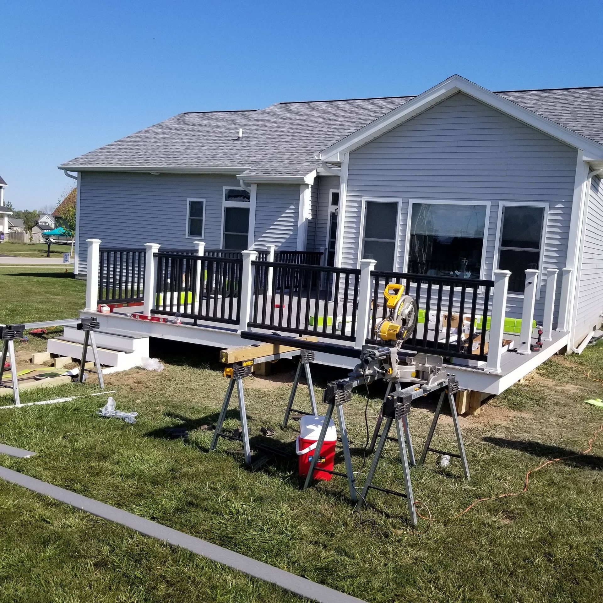Single-story gray house with a front porch under construction, tools and materials in the yard.