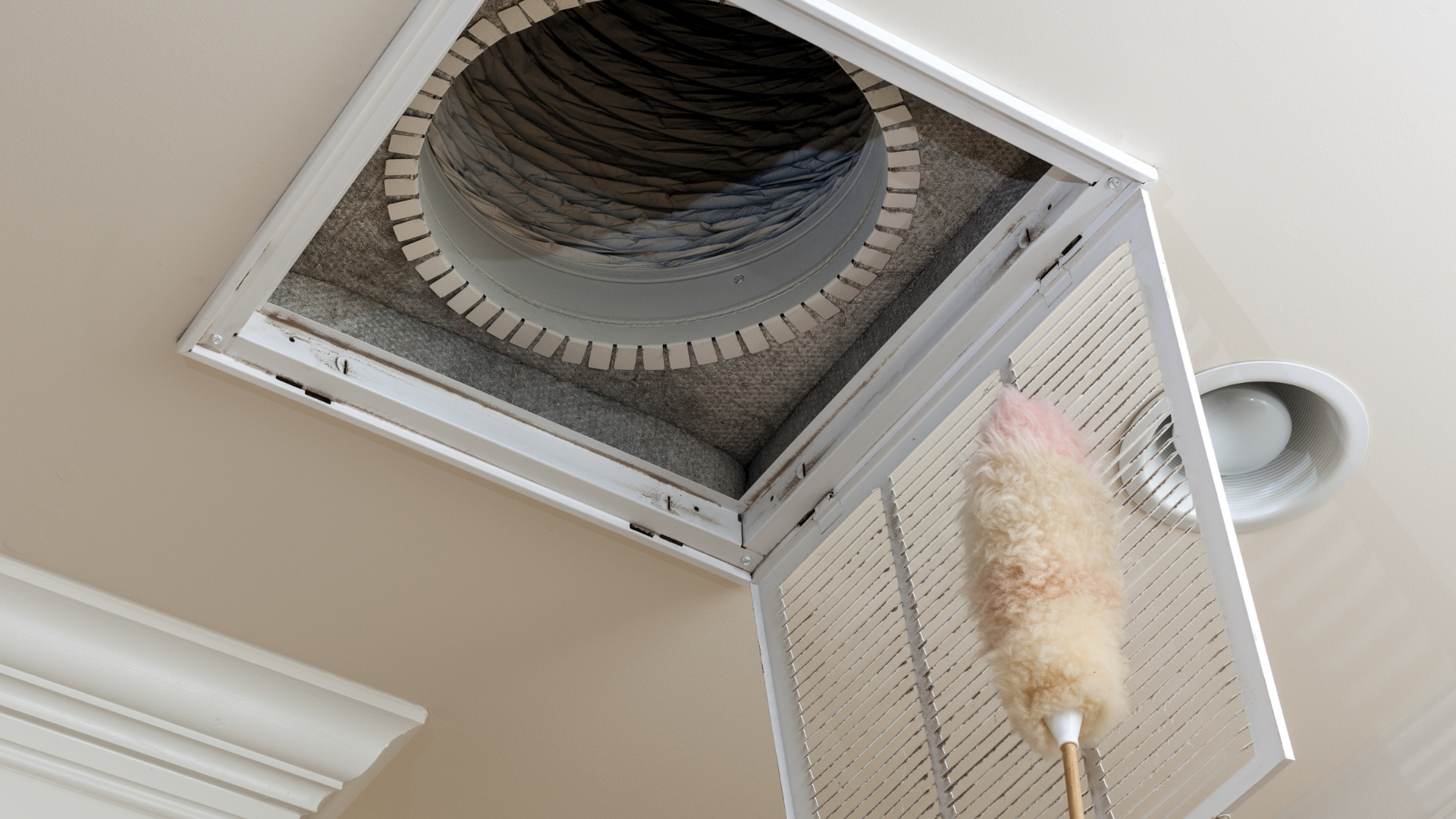 Close-up of a greasy range hood filter being removed for cleaning, illustrating a commonly overlooked kitchen crevice.
