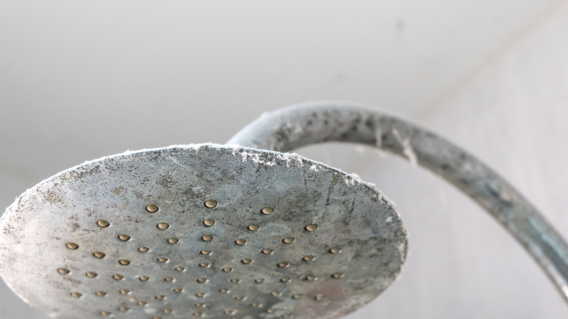 Close-up of a greasy range hood filter being removed for cleaning, illustrating a commonly overlooked kitchen crevice.