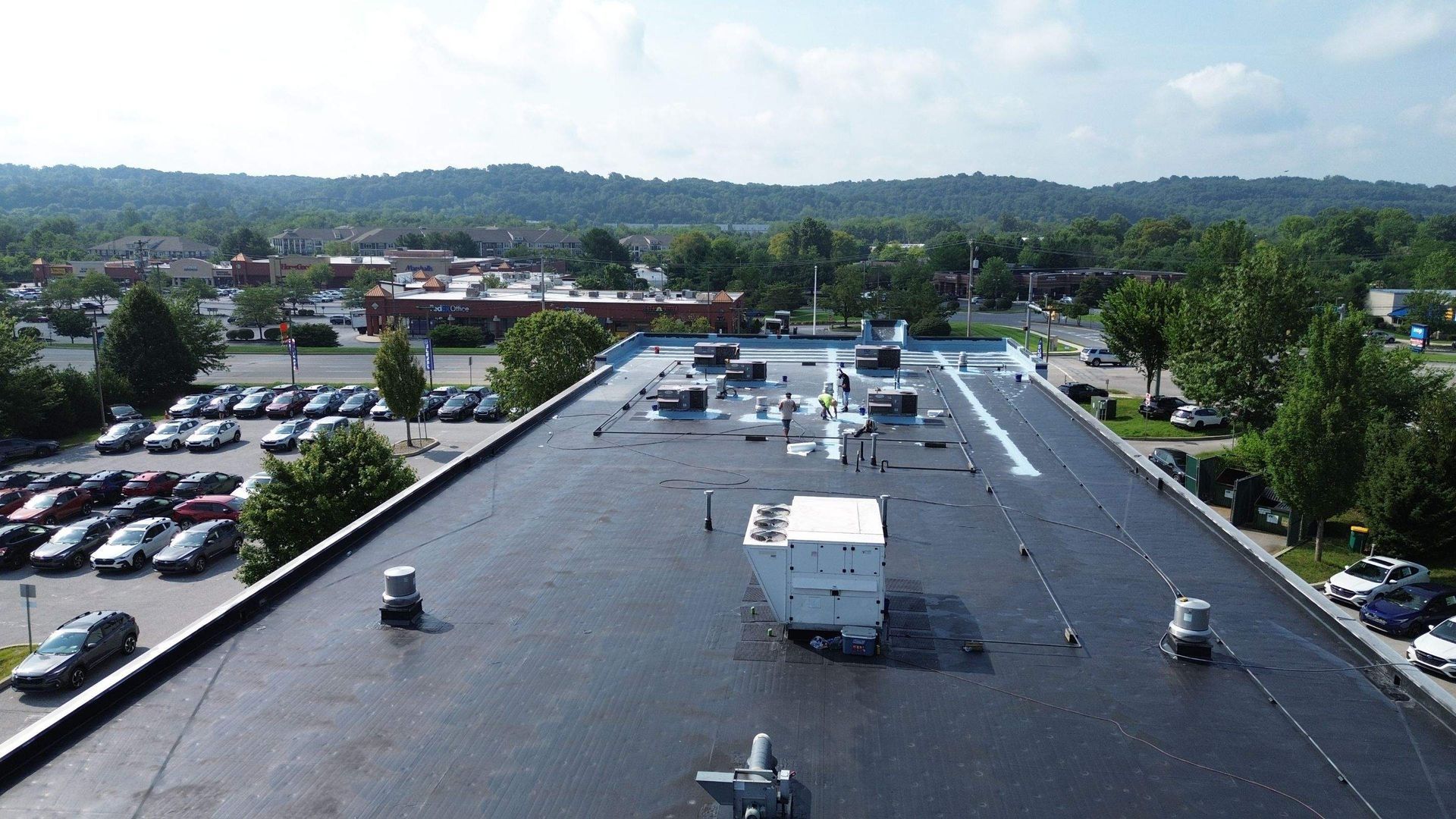 Overhead view of a gray warehouse with a curved metal roof, a yellow tanker truck, and green foliage nearby.