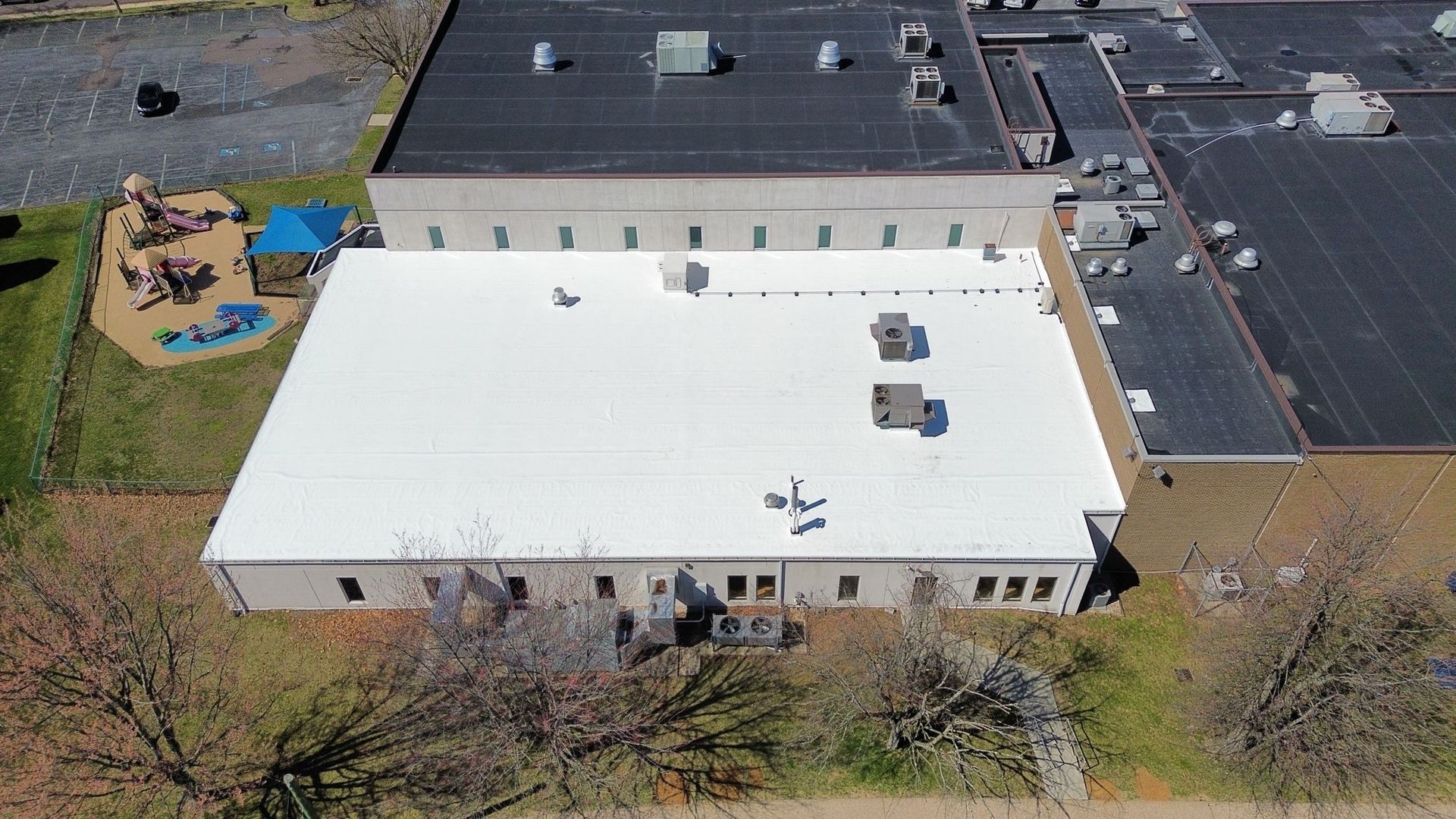 Flat commercial rooftop with HVAC units, white and gray surfaces, sunny day.