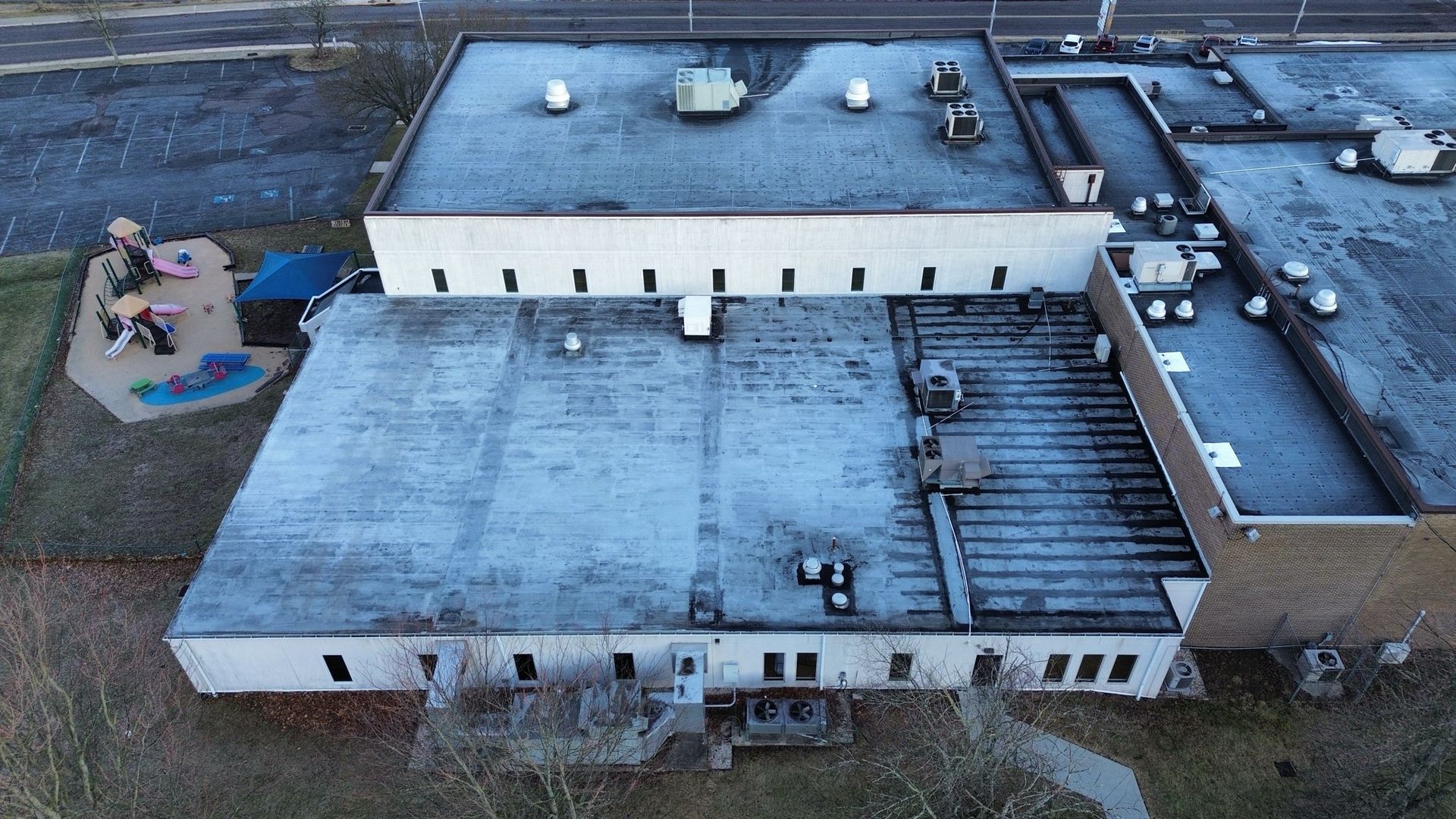White flat roof with cityscape background. Buildings and trees visible in sunlight.