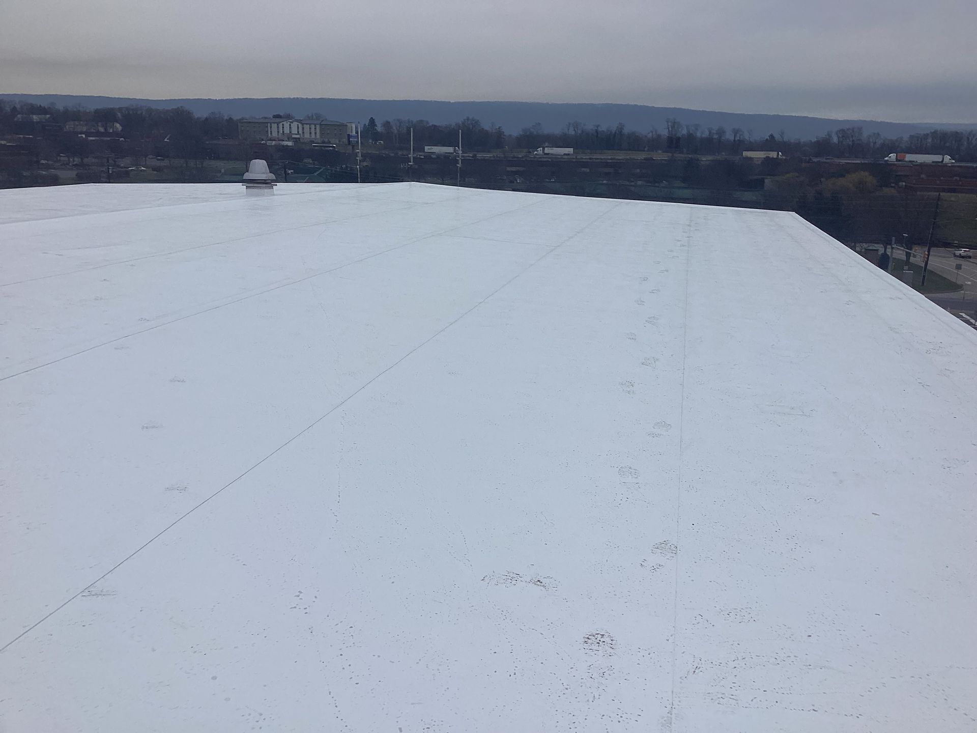 White commercial rooftop with cityscape in the background on a cloudy day.