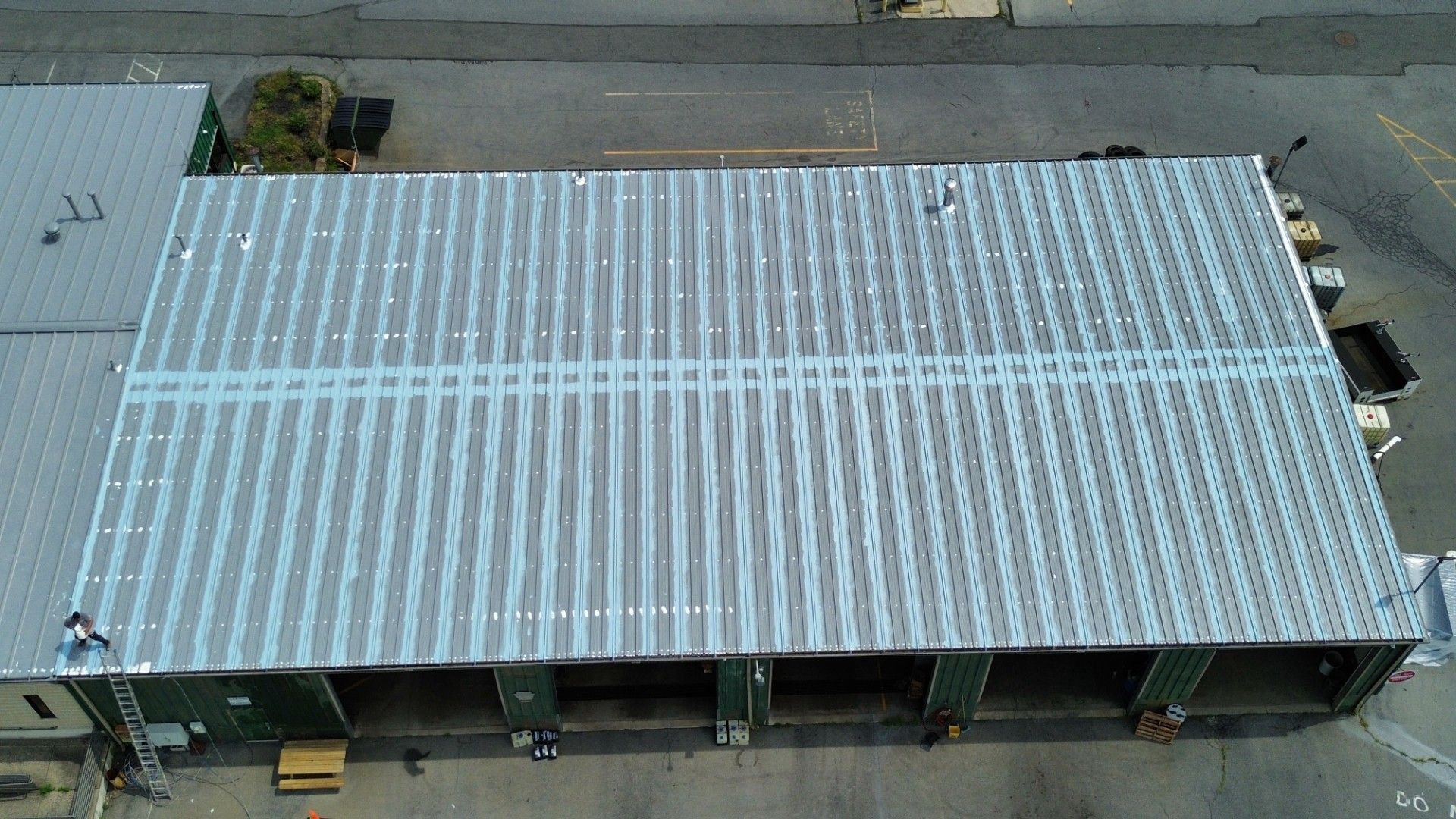 Overhead view of a corrugated metal roof on a warehouse with loading docks.