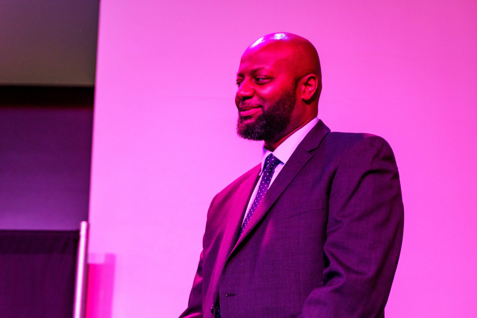 a man in a suit and tie is standing in front of a pink wall