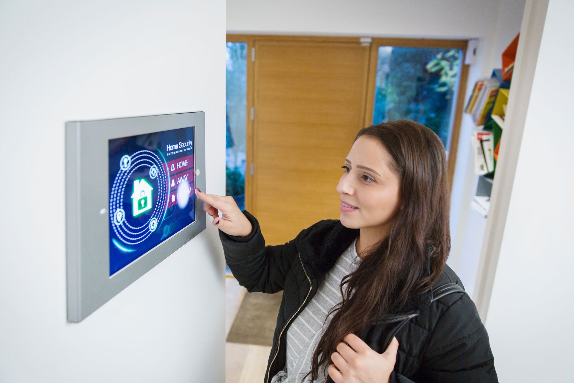 A woman leaving her house, setting a smart domestic burglar alarm system.