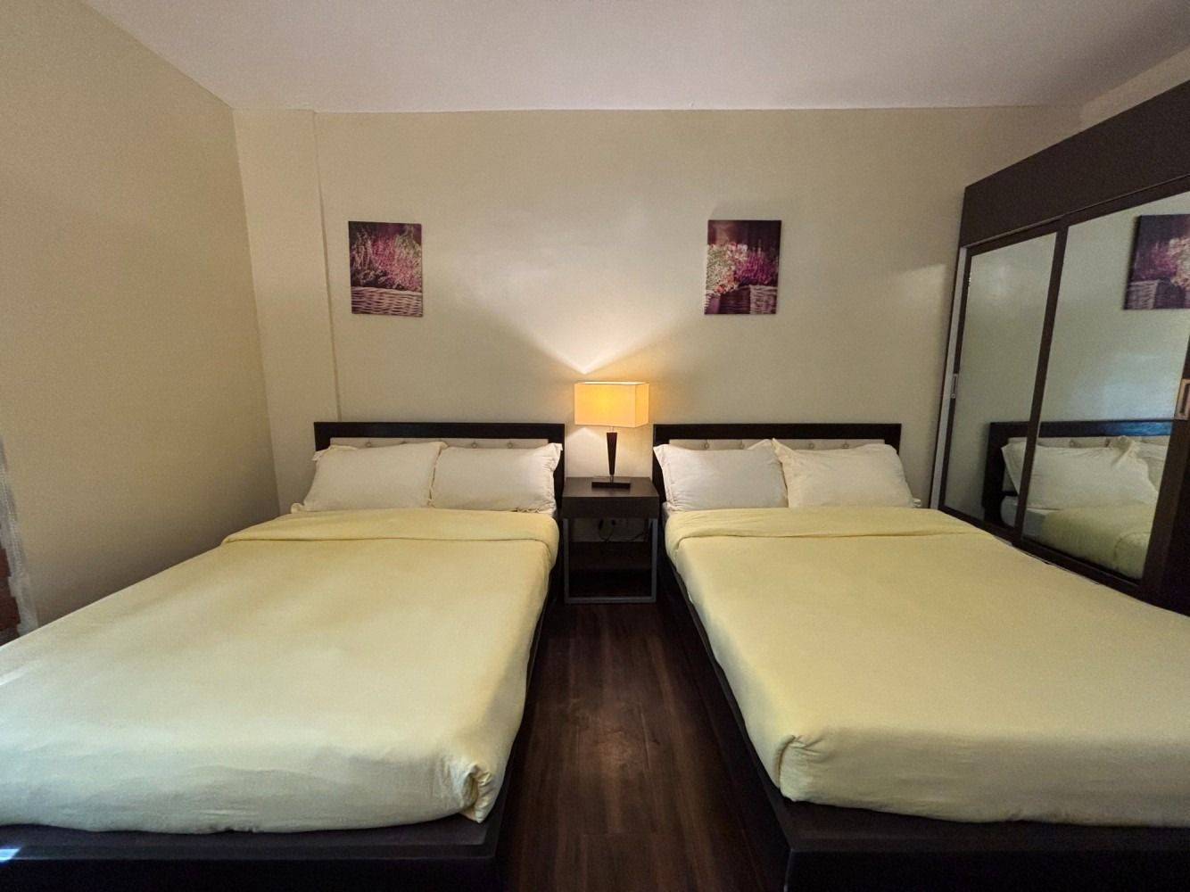 Two twin beds in a bedroom, with a nightstand and lamp between them.