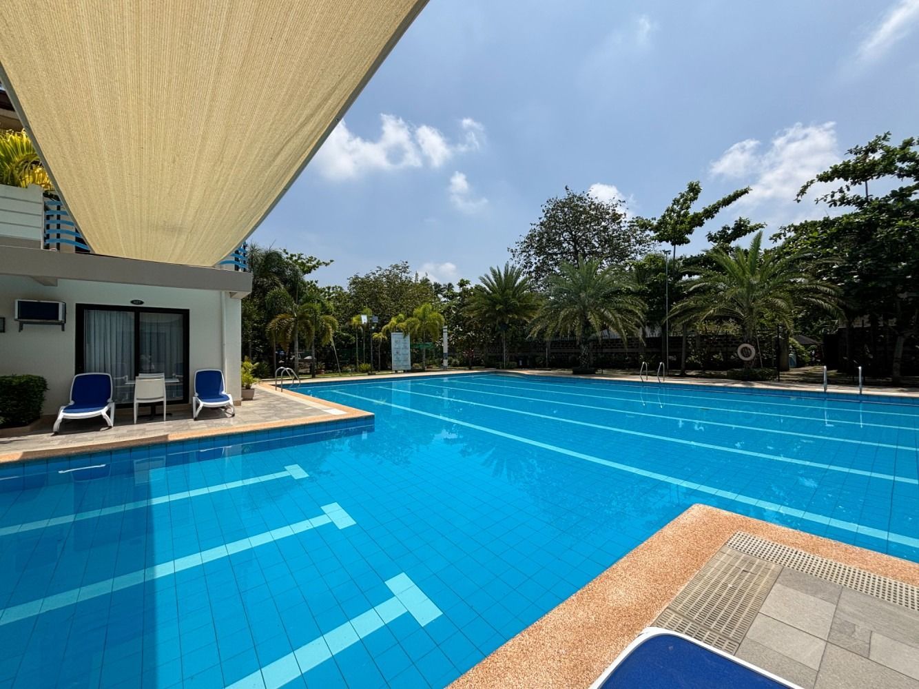 Swimming pool under a bright blue sky with shade.