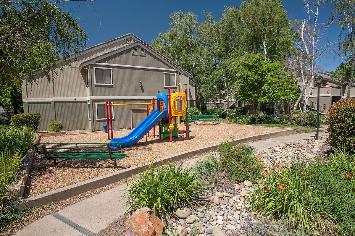 Playground at a multifamily property with a blue slide and colorful equipment.