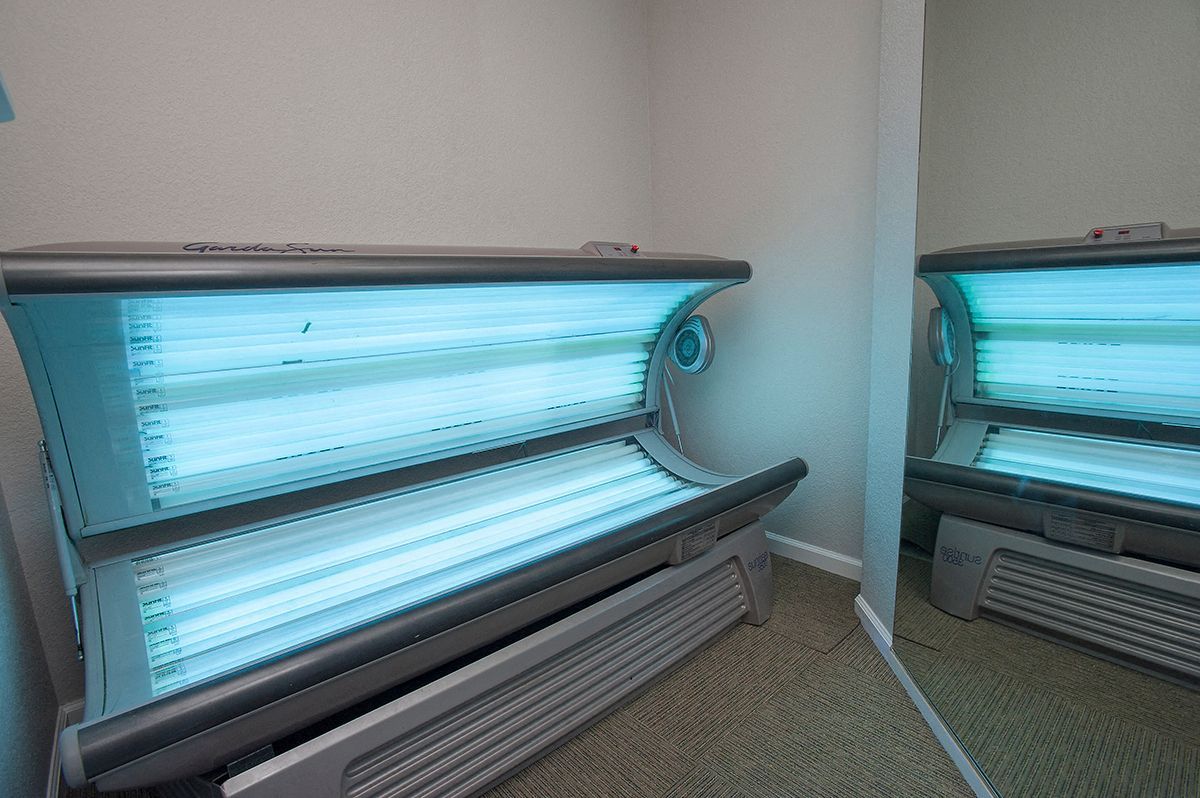 Two tanning beds in a small, mirror-lined wellness room.