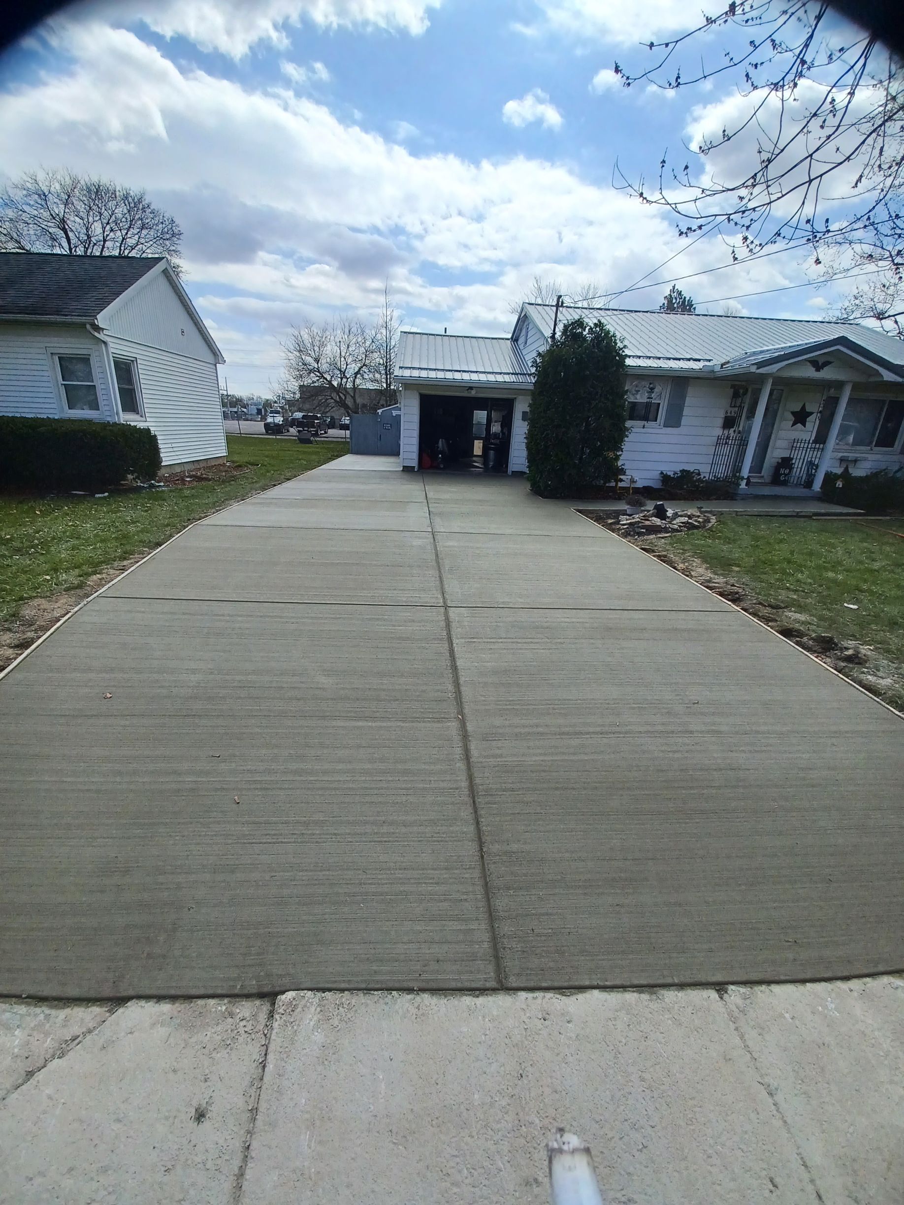 A concrete driveway leading to a house on a sunny day.