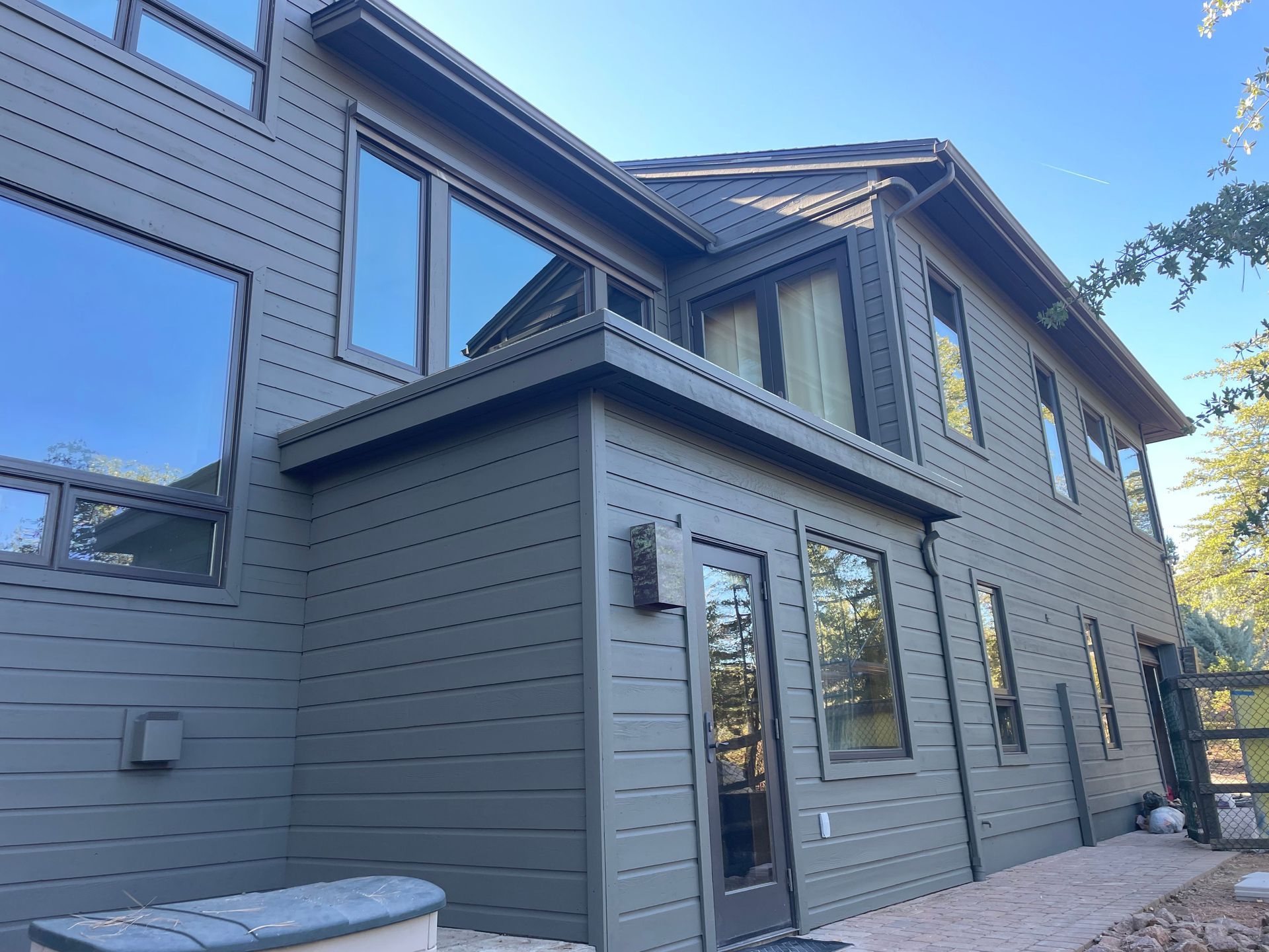A person is painting a wooden railing with a blue brush.