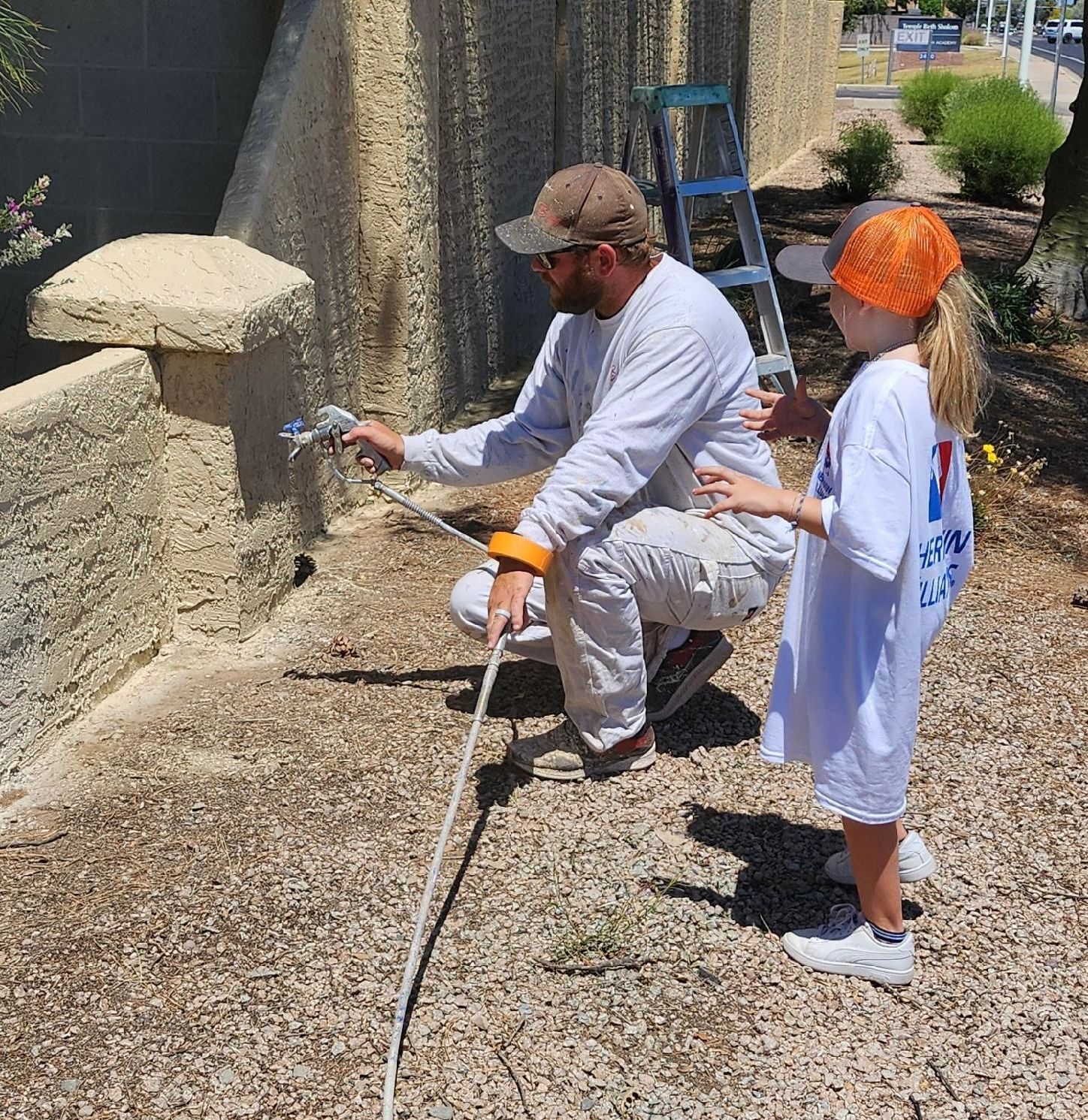 A man and a girl are painting a wall together