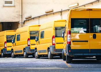 a row of yellow vans parked in front of a building .