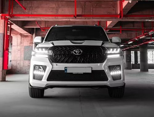 White Toyota Land Cruiser SUV with black grill, parked in a concrete garage.