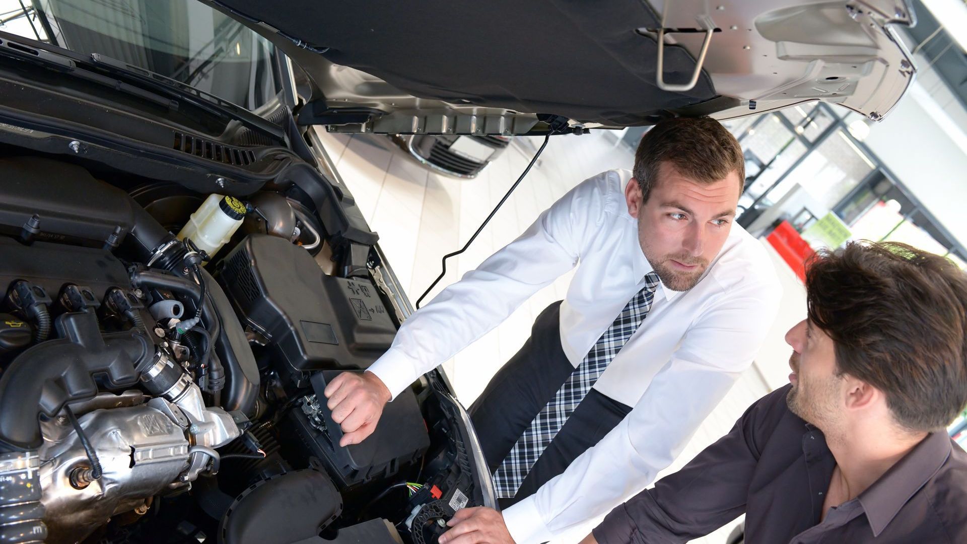 Un homme en uniforme bleu tient deux clés devant une voiture.