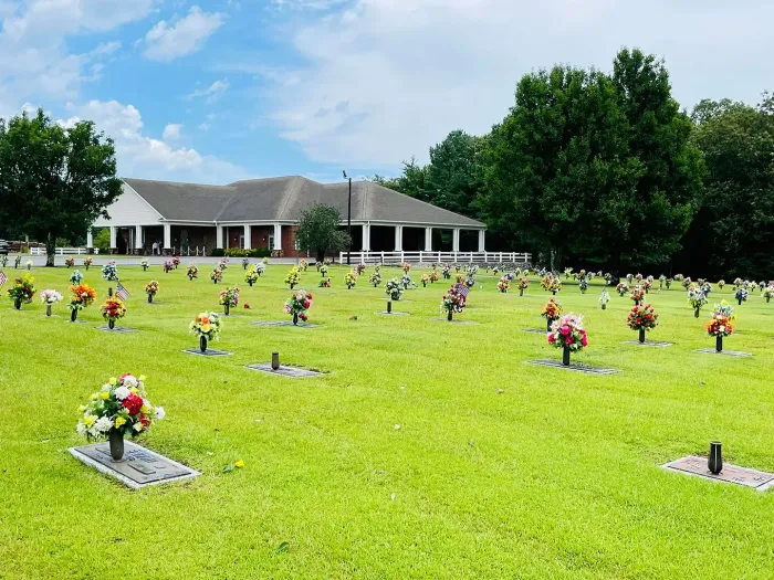 Rendering of a memorial with a central cross and surrounding structures, trees, and sky.