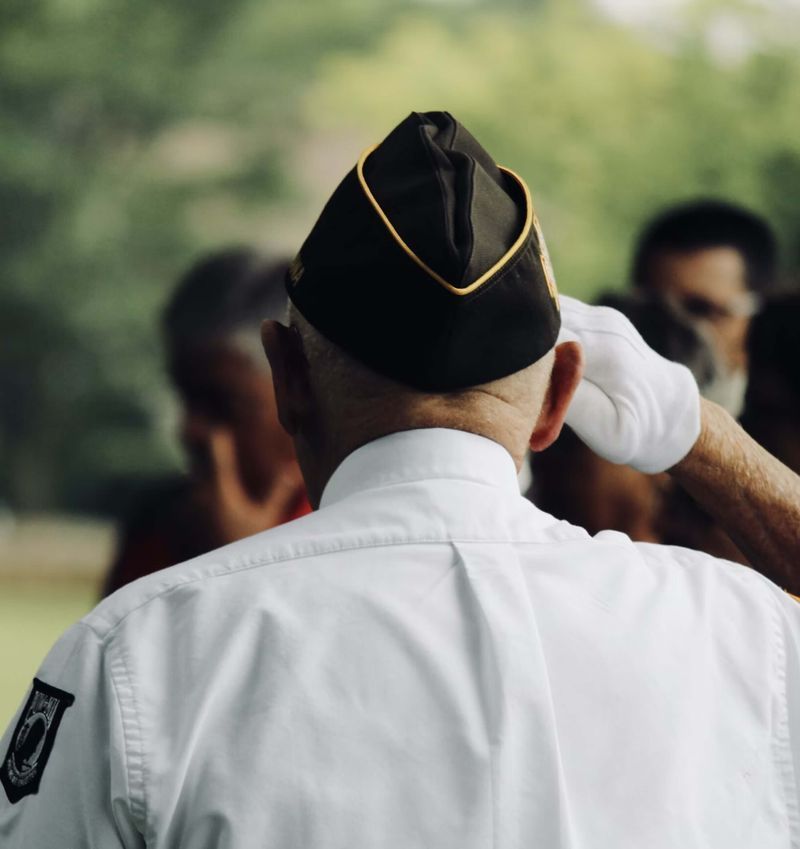 A man wearing a black hat and white gloves salutes