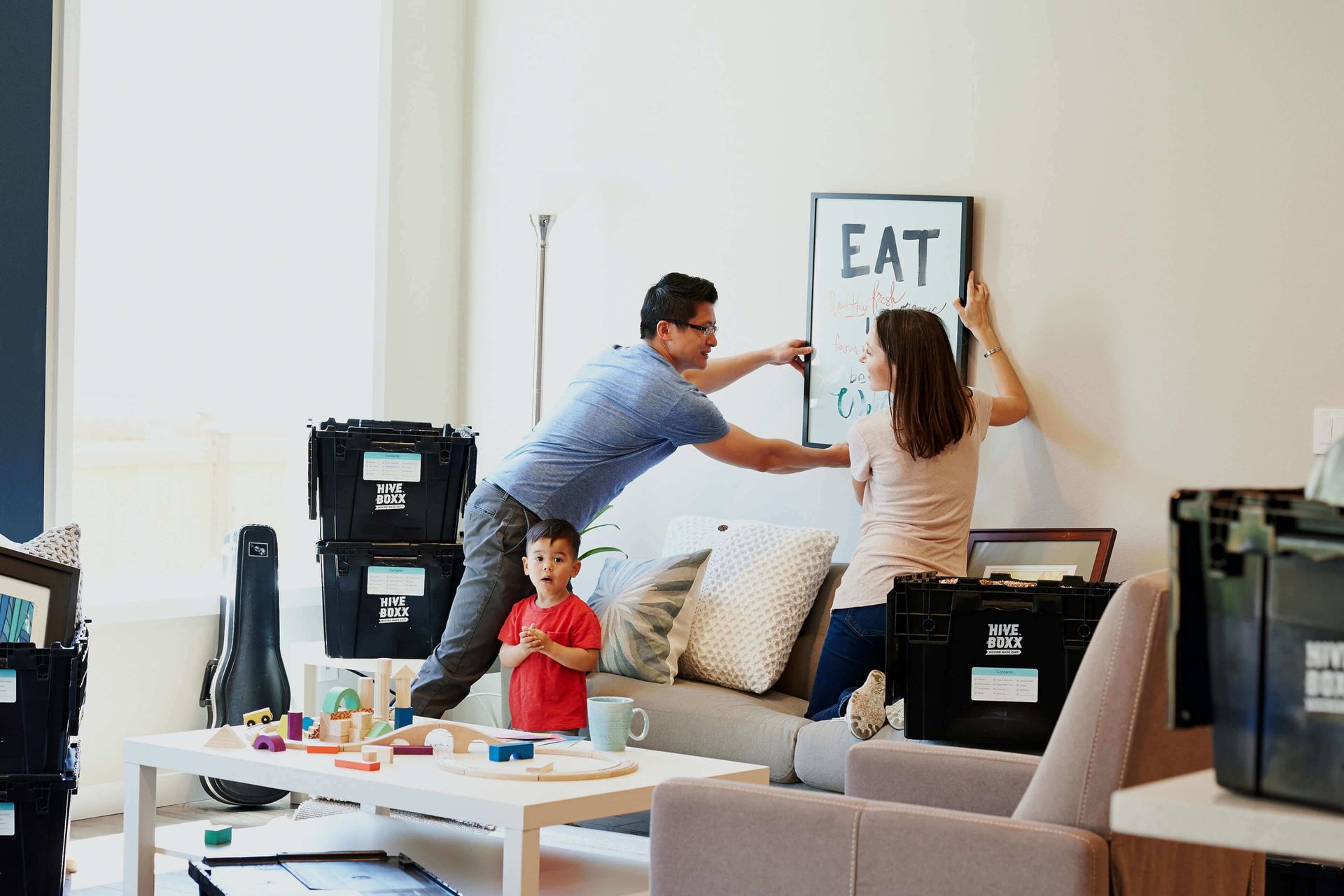 A family is moving into a new home and hanging a picture on the wall.