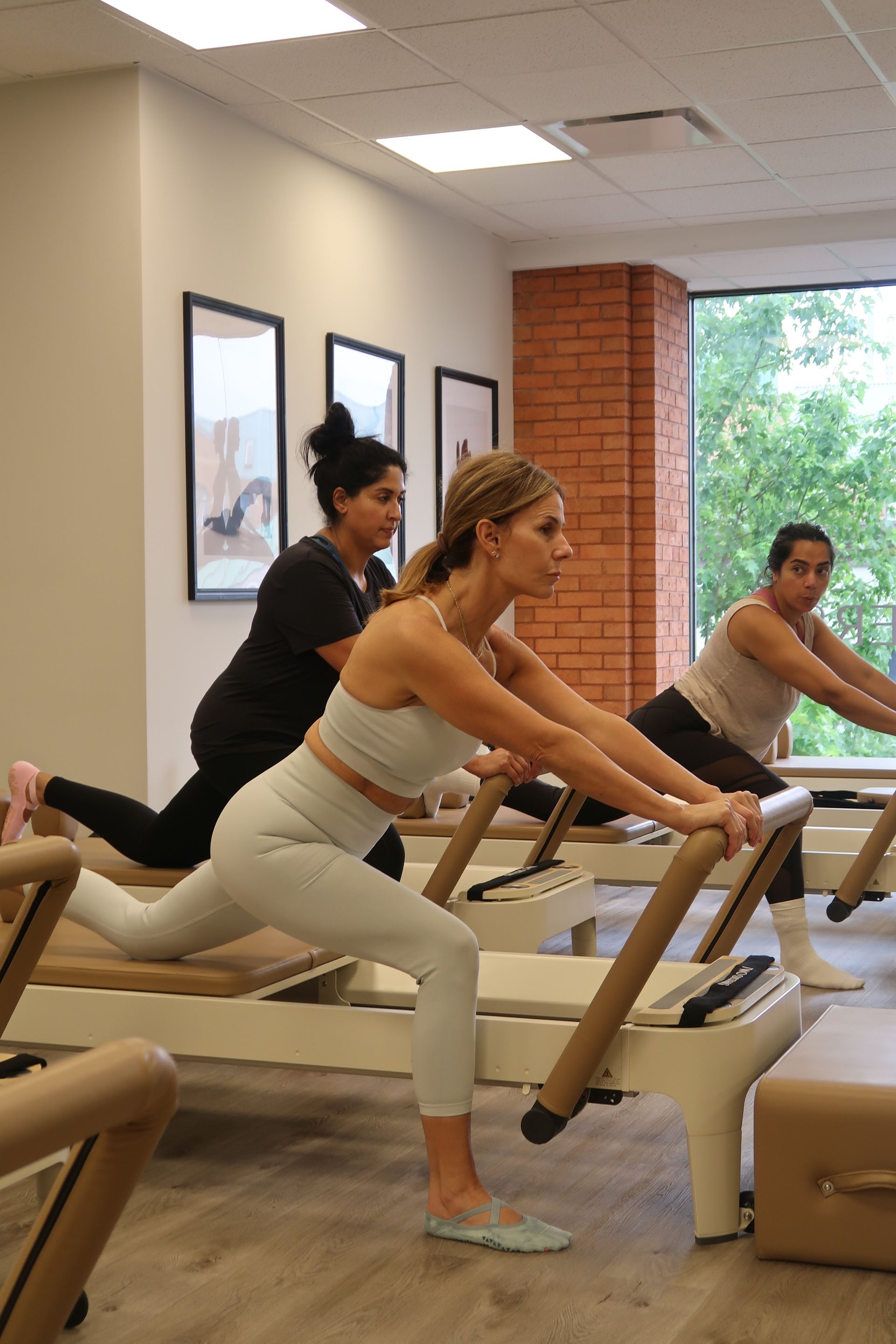 Reformer Pilates class in Oakville showing women performing controlled low impact full body exercise