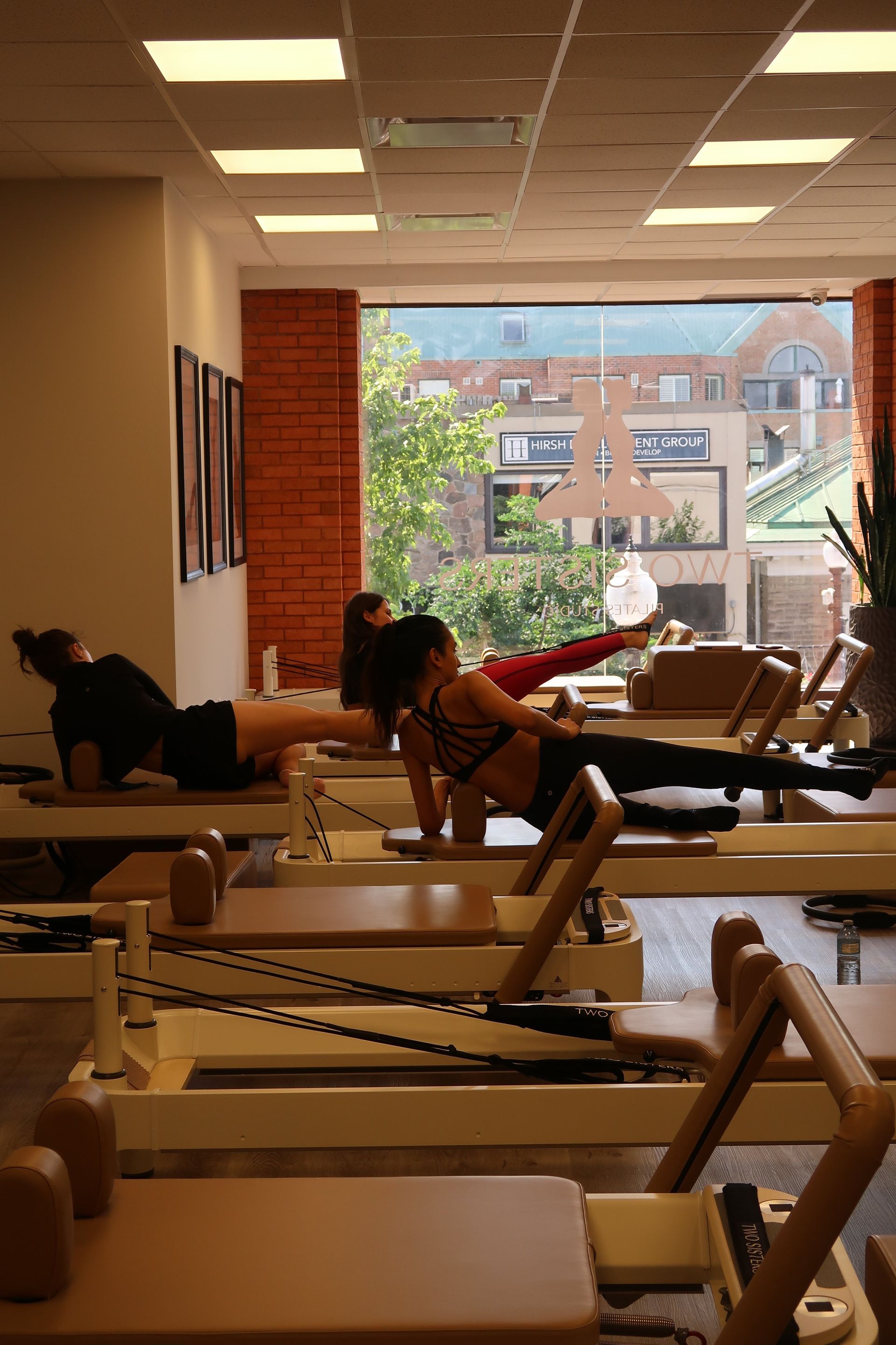 Reformer Pilates class at Two Sisters Pilates studio with clients performing Pilates