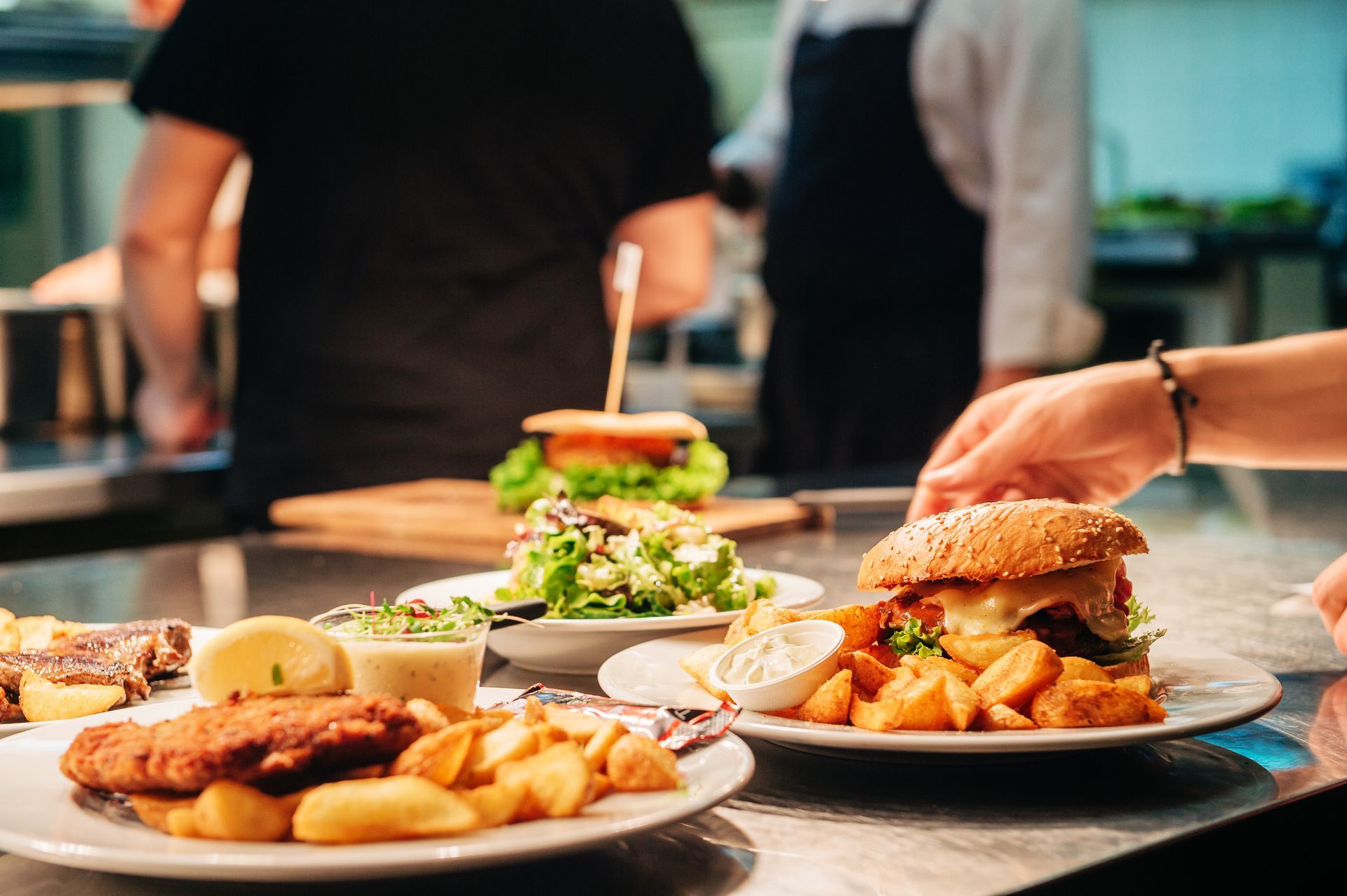 A person is putting a hamburger on a plate in a restaurant kitchen.