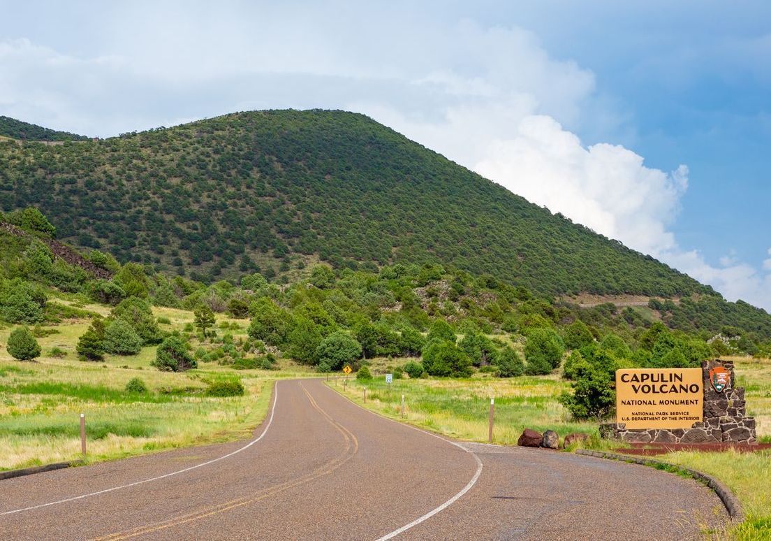 A road with a mountain in the background and a sign on the side of it.