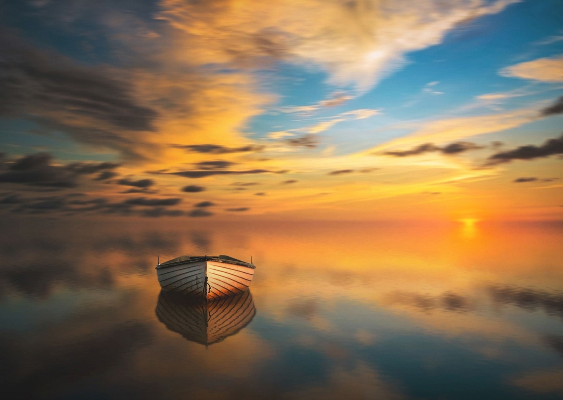 A boat is floating on top of a body of water at sunset.
