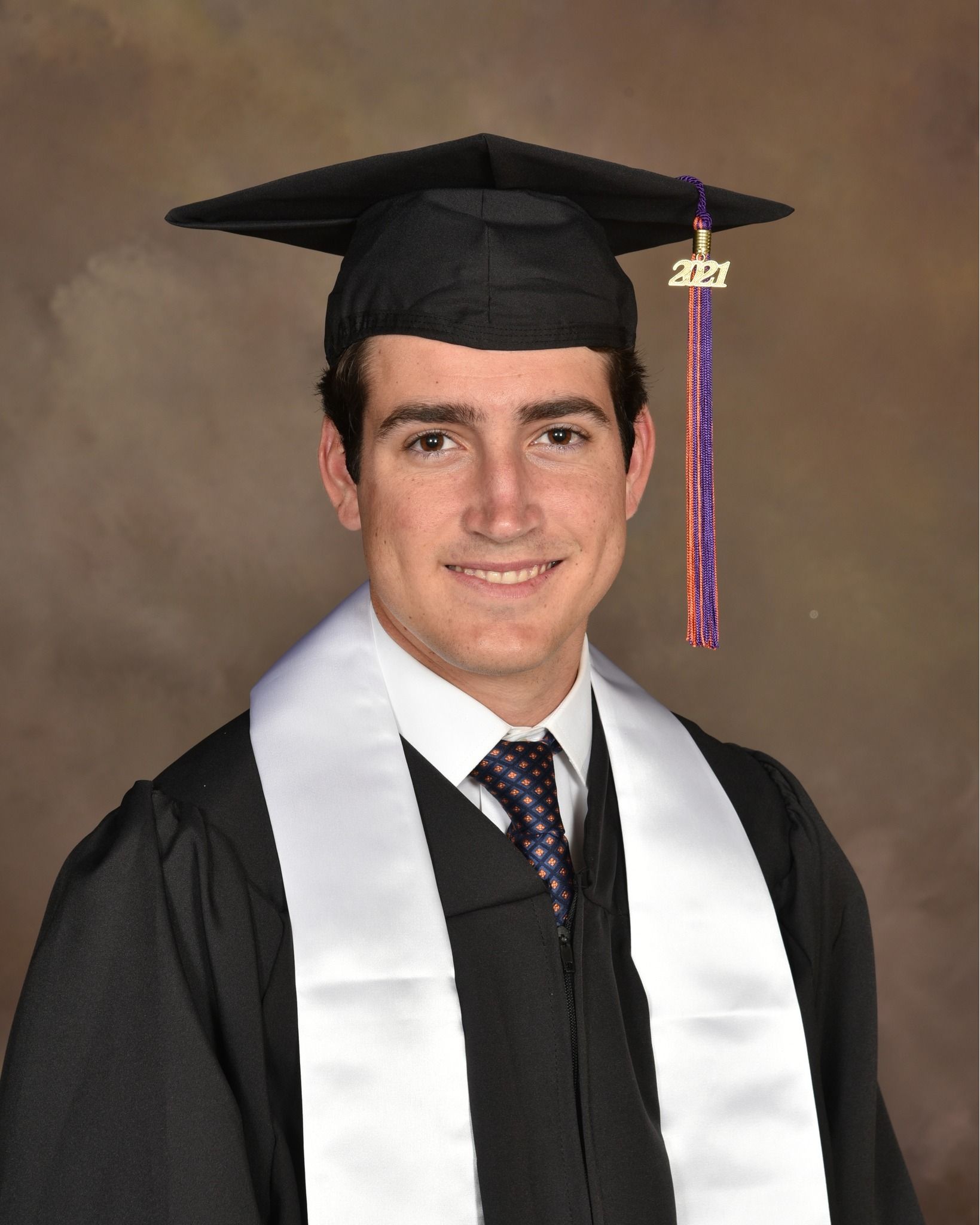 A man wearing a graduation cap and gown with the year 2021 on it
