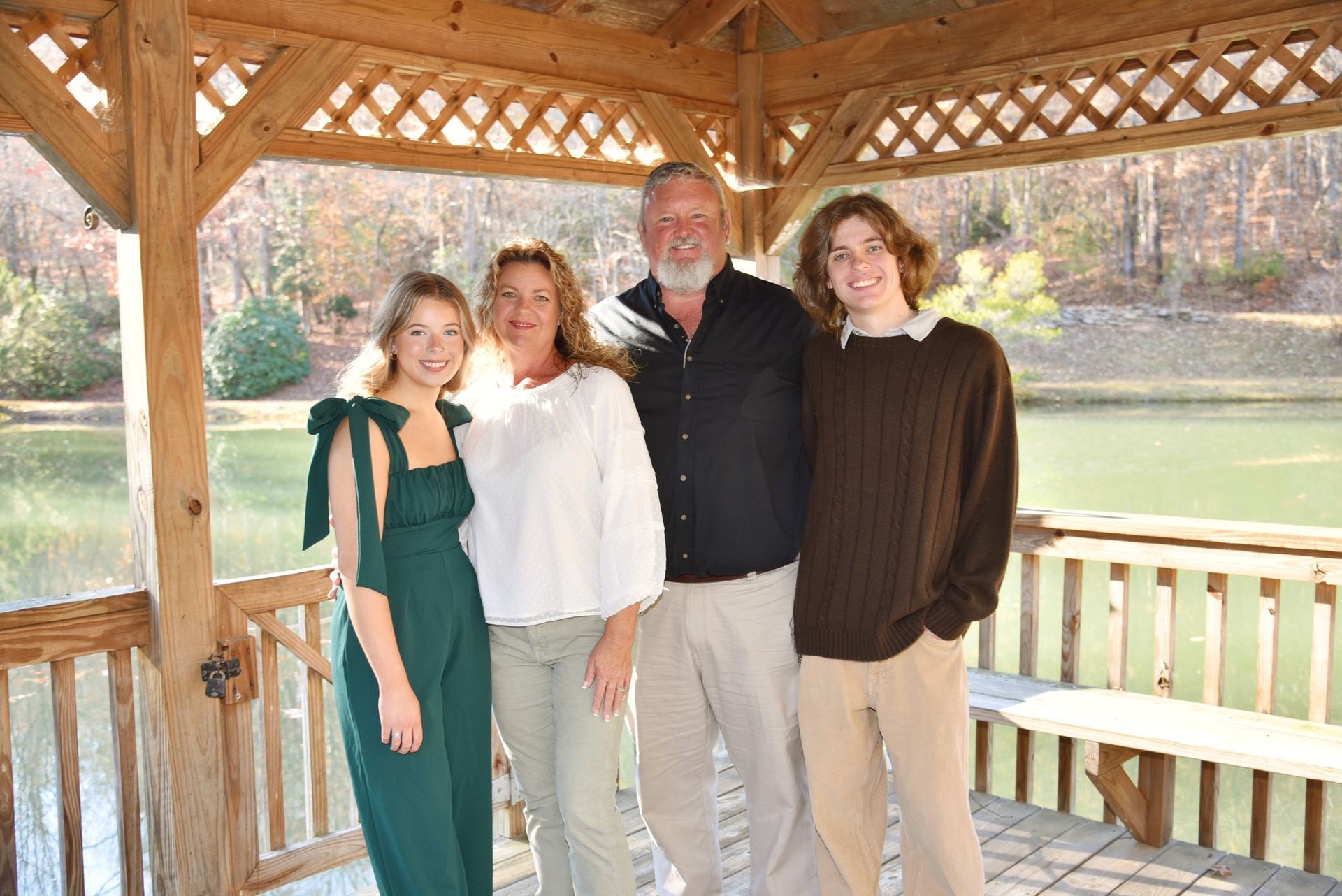 A family is posing for a picture in front of a gazebo overlooking a lake.