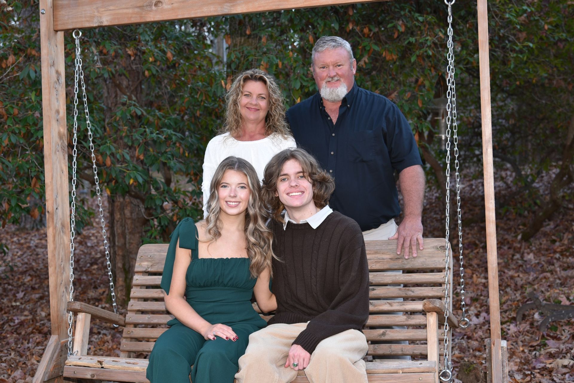 A family is posing for a picture on a wooden swing.