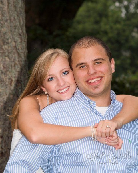 A man and woman are posing for a picture and the woman is wearing a wedding ring
