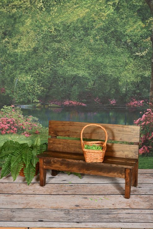 A wooden bench with a basket on it in front of a lake.