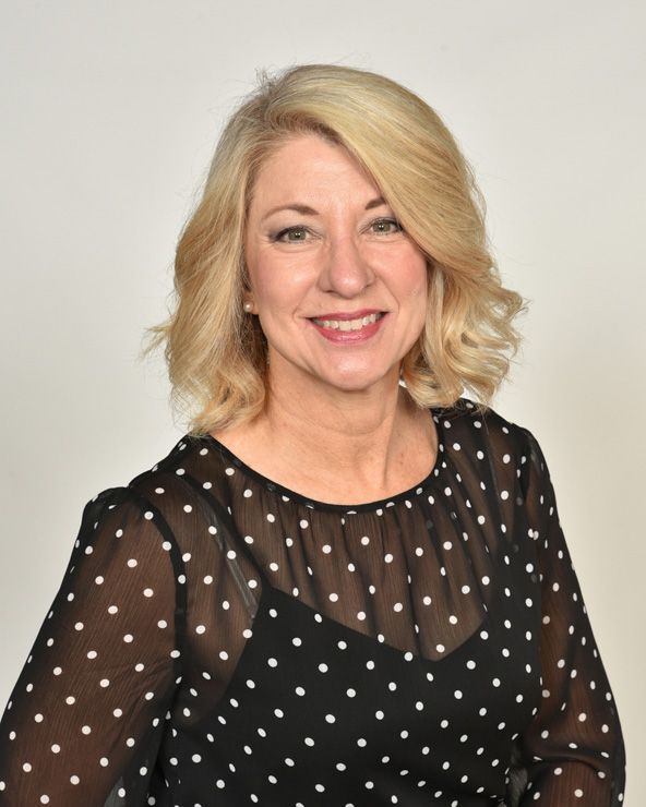 A woman wearing a black and white polka dot dress smiles for the camera
