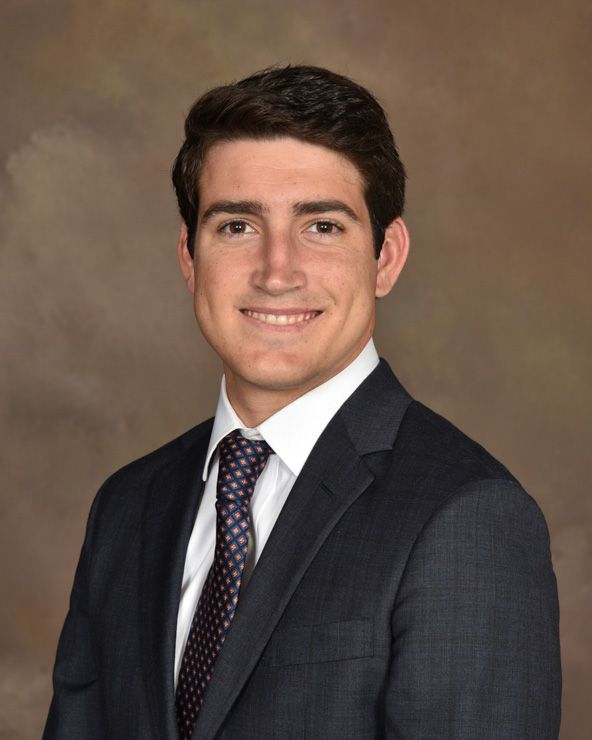 A man in a suit and tie is smiling for the camera